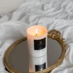 luxury-scented-candle-pearl-collection-lit-up-white-vessel-white-wax-on-a-mirror