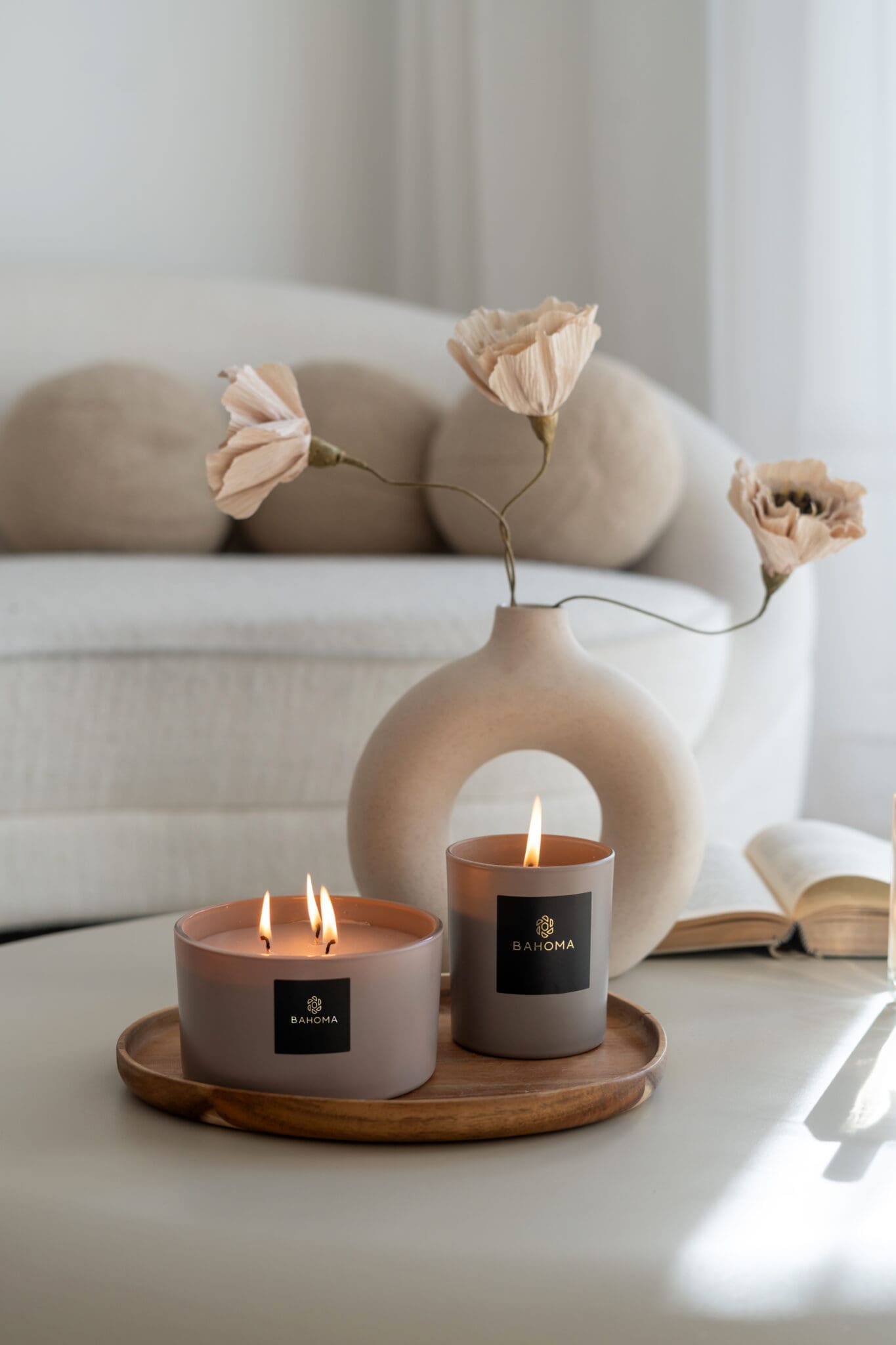 luxury-scented-candle-sand-collection-lit0up-satin-taupe-mocca-glass-vessel-mocca-taupe-wax-on-a-coffee-table-luxury-steeing-with-vase