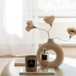 luxury-scented-candle-sand-collection-satin-taupe-mocca-glass-vessel-mocca-taupe-wax-on-a-coffee-table-luxury-steeing-with-vase