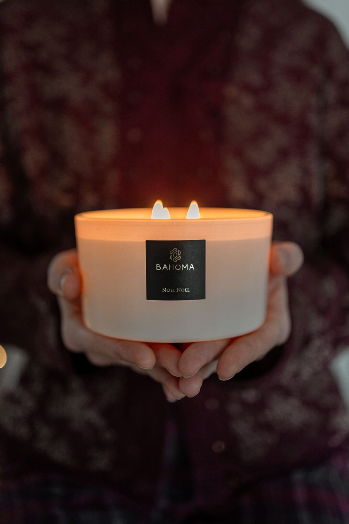 Beautiful noel noel white 3 wick candle offered as gift, held in hands