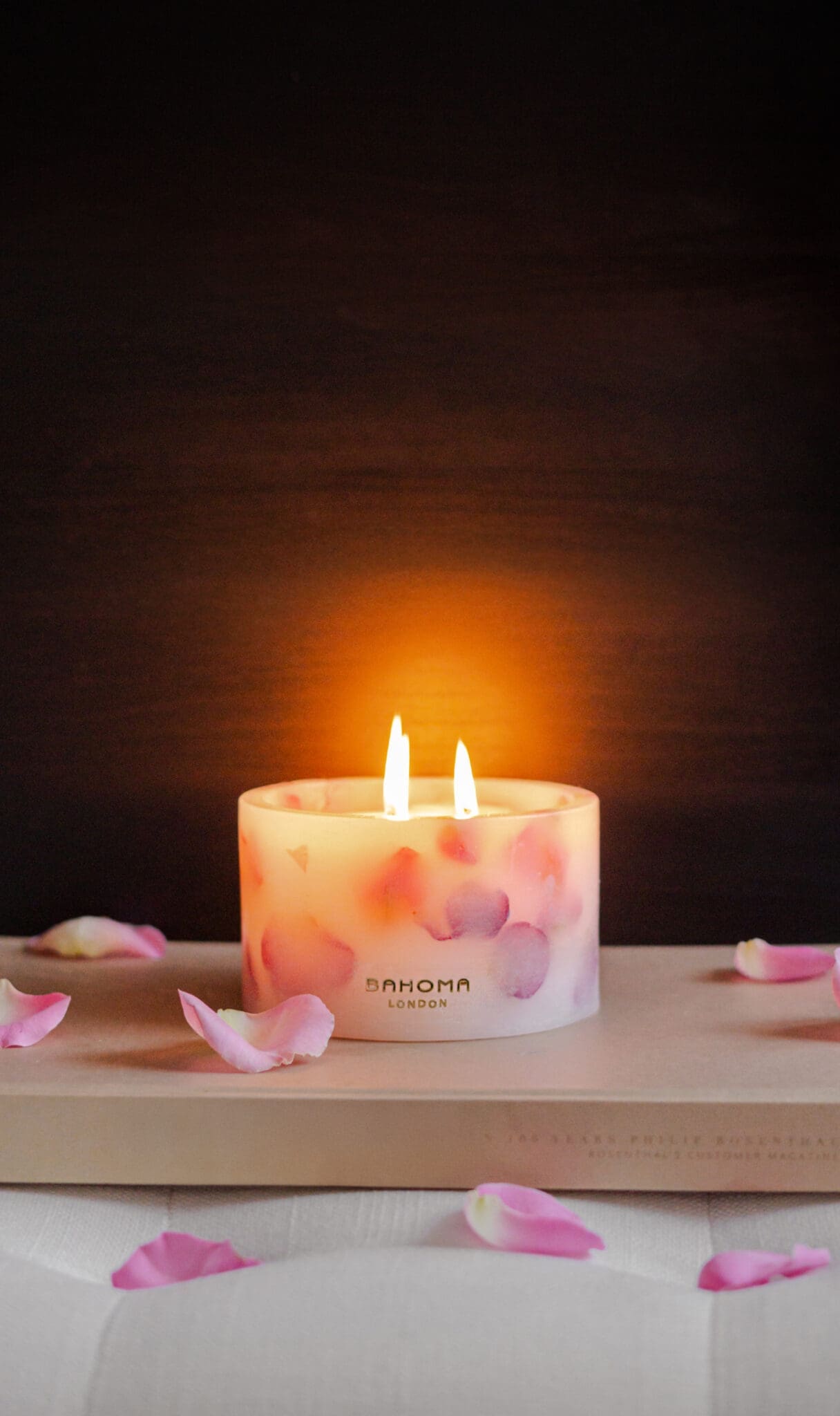 Lit up Velvet Rose - Small Pillar Candle made with real rose petals held in hand on a dark moody background with a glow
