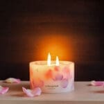 Lit up Velvet Rose - Small Pillar Candle made with real rose petals held in hand on a dark moody background with a glow
