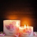 Lit up Velvet Rose - Small Pillar Candle made with real rose petals on a dark moody background with a glow, accompanied by a Grand pillar in same design