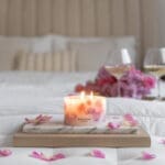 Lit up Velvet Rose - Small Pillar Candle made with real rose petals on bed side on a tray