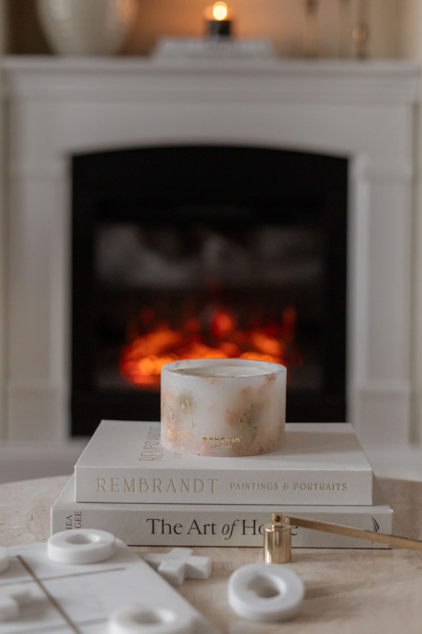 Cherry Blossom Scented Grand Pillar Candle on a white book with dried real cherry blossom petals in front of fire place in lifestyle setting