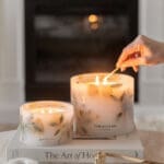 Close up of the Amalfi Coast Scented Grand Pillar Candle highlighting its large scale and clean white wax. A hand visible lighting up the candle.