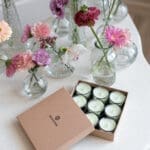 Primrose & Amberwood – Nine Lights Candle Set | Alchemy Collection. Lifestyle image showing open box containing nine mini candles in pastel green colour.