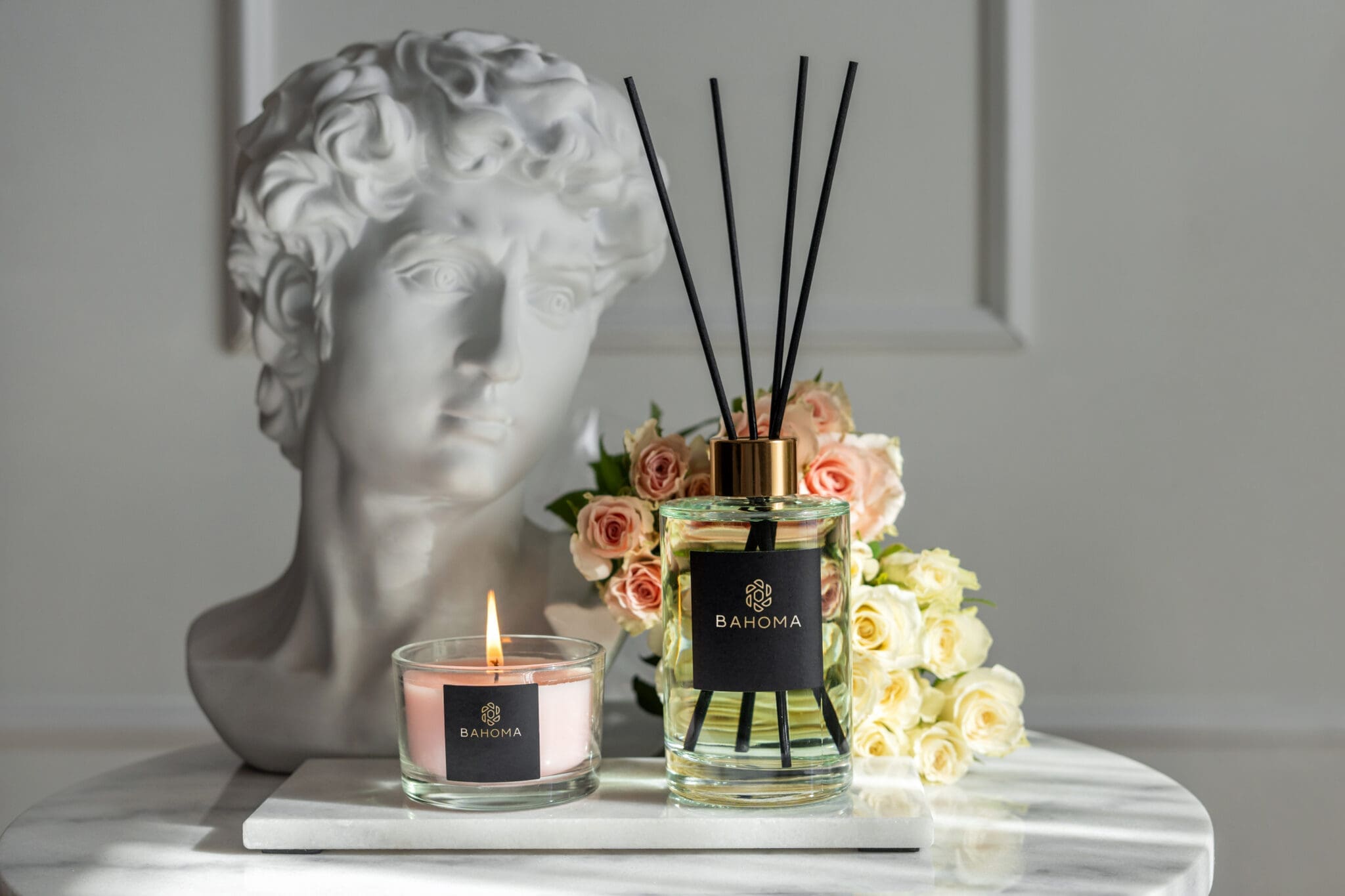 primrose-and-amberwood-200ml-fragranced-diffuser-alchemy-with-a-compact-candle-and-clay-bust-with-a-vase-and-flowers-in-the-background