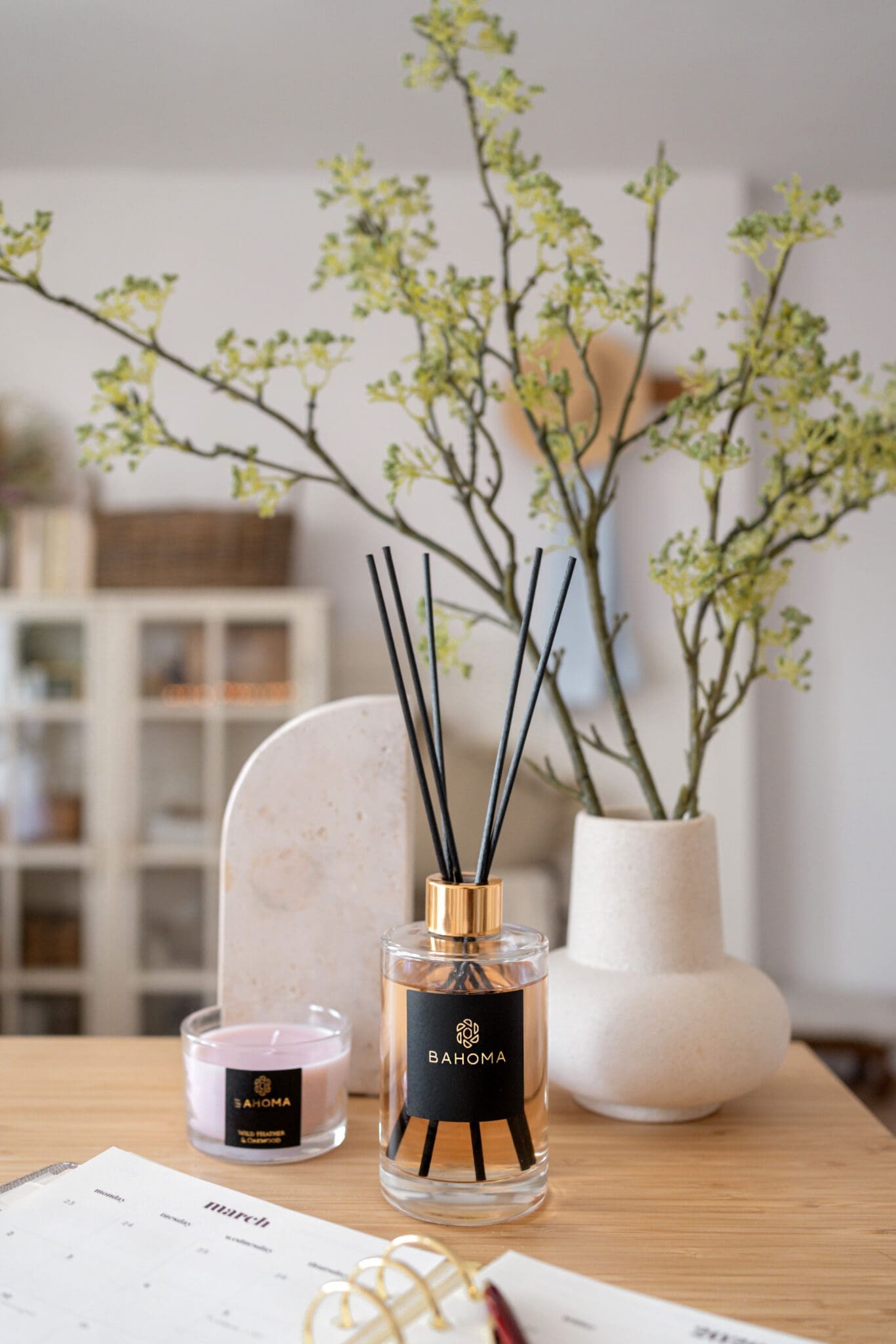 velvet-peony-and-cashmere-200ml-fragranced-diffuser-alchemy-with-black-reeds-on-a-table-with-compact-candle-and-a-cream-vase