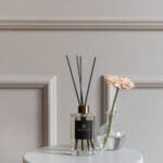 wild-heather-and-oakwood-200ml-diffuser-alchemy-collection-with-black-reeds-on-a-table-with-a-small-vase-with-gerbera-flower